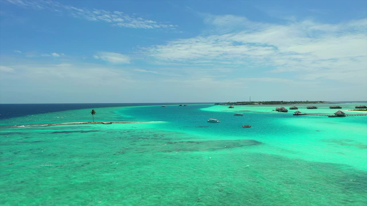 在阳光明媚的日子里，游客度假胜地在海上拍摄的海上船只的空中前进镜头-马尔代夫的thulushoo视频素材