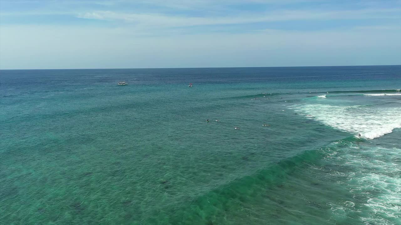 航拍人们在海浪中冲浪板游泳，无人机在阳光灿烂的日子里向前飞行-马尔代夫的thulushoo视频素材