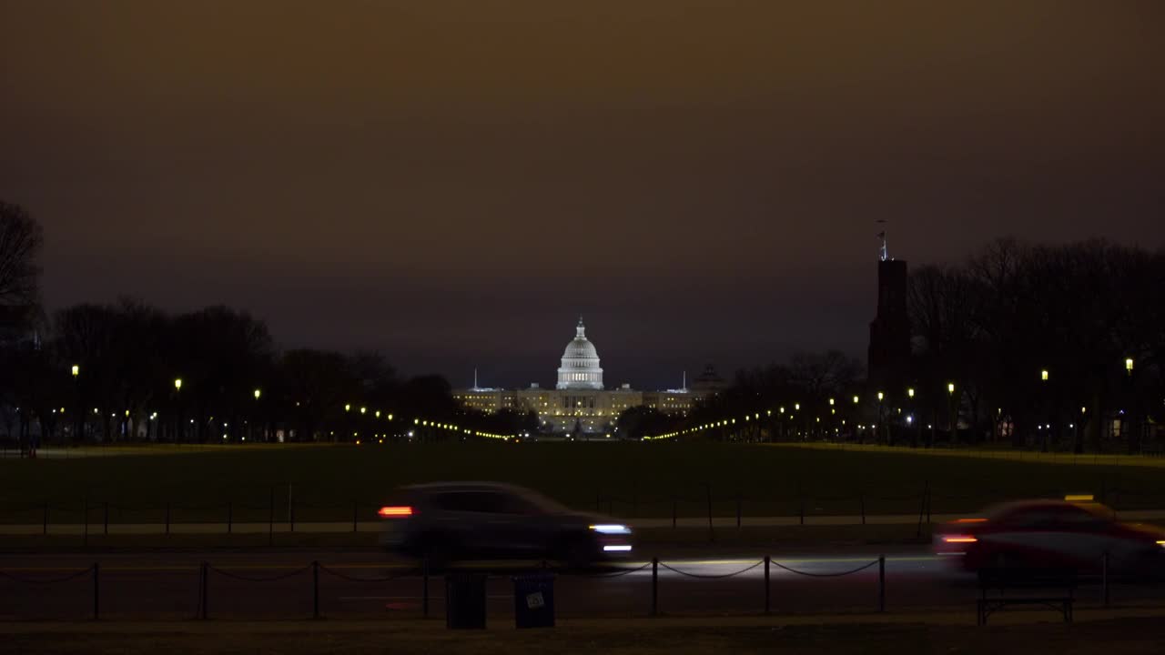 灯火通明的美国国会大厦的封锁镜头，汽车在路上行驶，夜晚天空晴朗——华盛顿，哥伦比亚特区视频素材