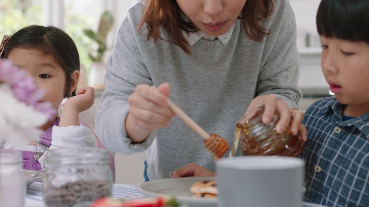 快乐的亚洲家庭吃煎饼早餐，孩子们享受健康的自制餐与父母在周末早上在厨房4k镜头视频素材