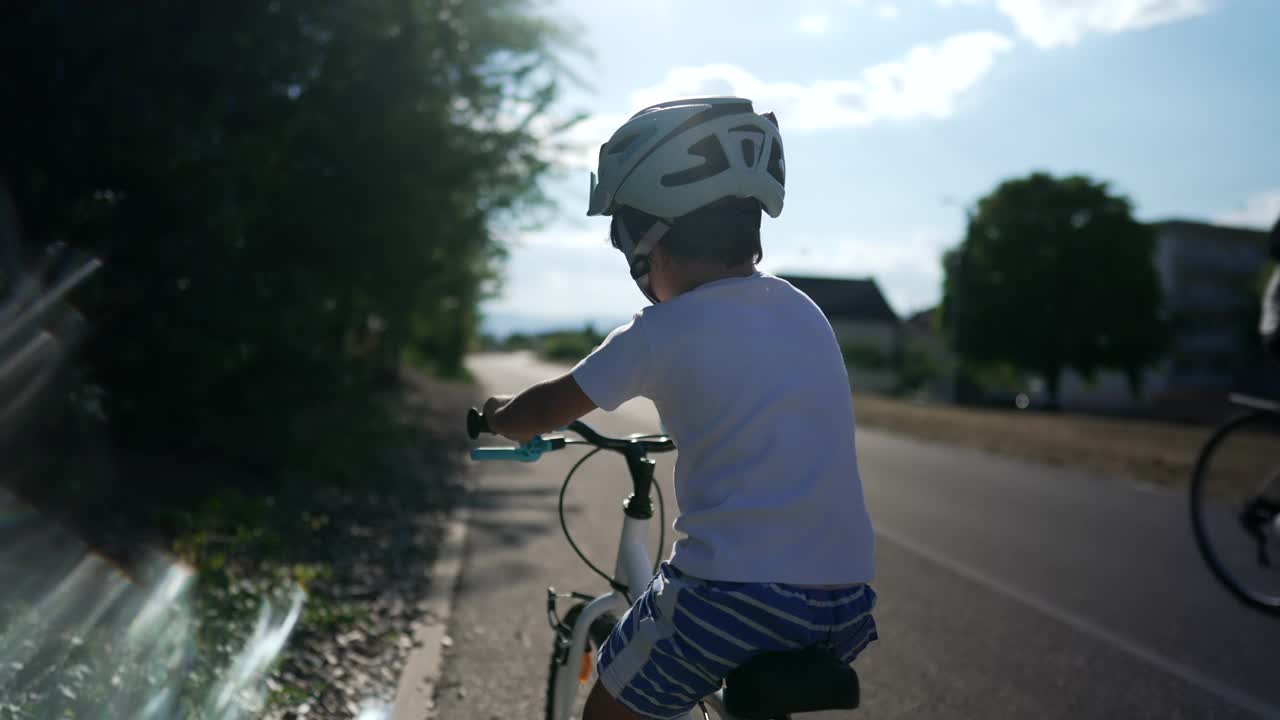 骑自行车的孩子戴着头盔在自行车城市道路上学习骑自行车。小男孩骑自行车。积极的孩子锻炼保持平衡视频素材