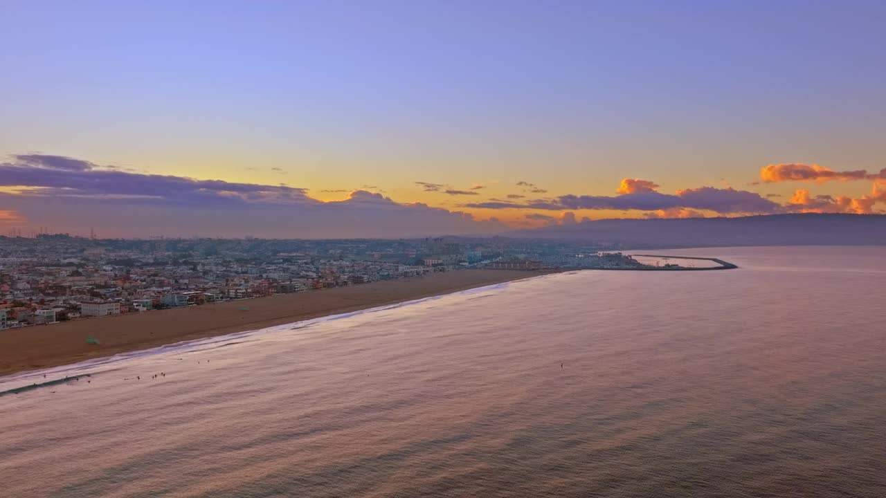 加利福尼亚州赫莫萨海滩海滨城市背后的戏剧性日落的空中上升镜头视频素材