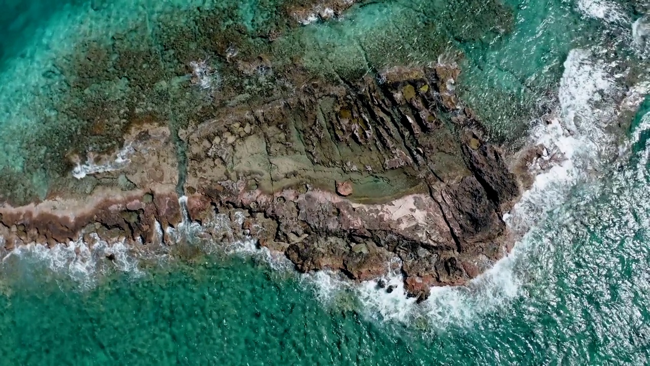 高空俯视拍摄的石头海岸线和绿松石海水被太阳照亮视频素材