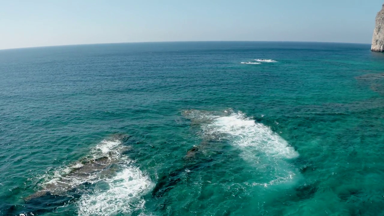 高空俯视拍摄的石头海岸线和绿松石海水被太阳照亮。视频素材