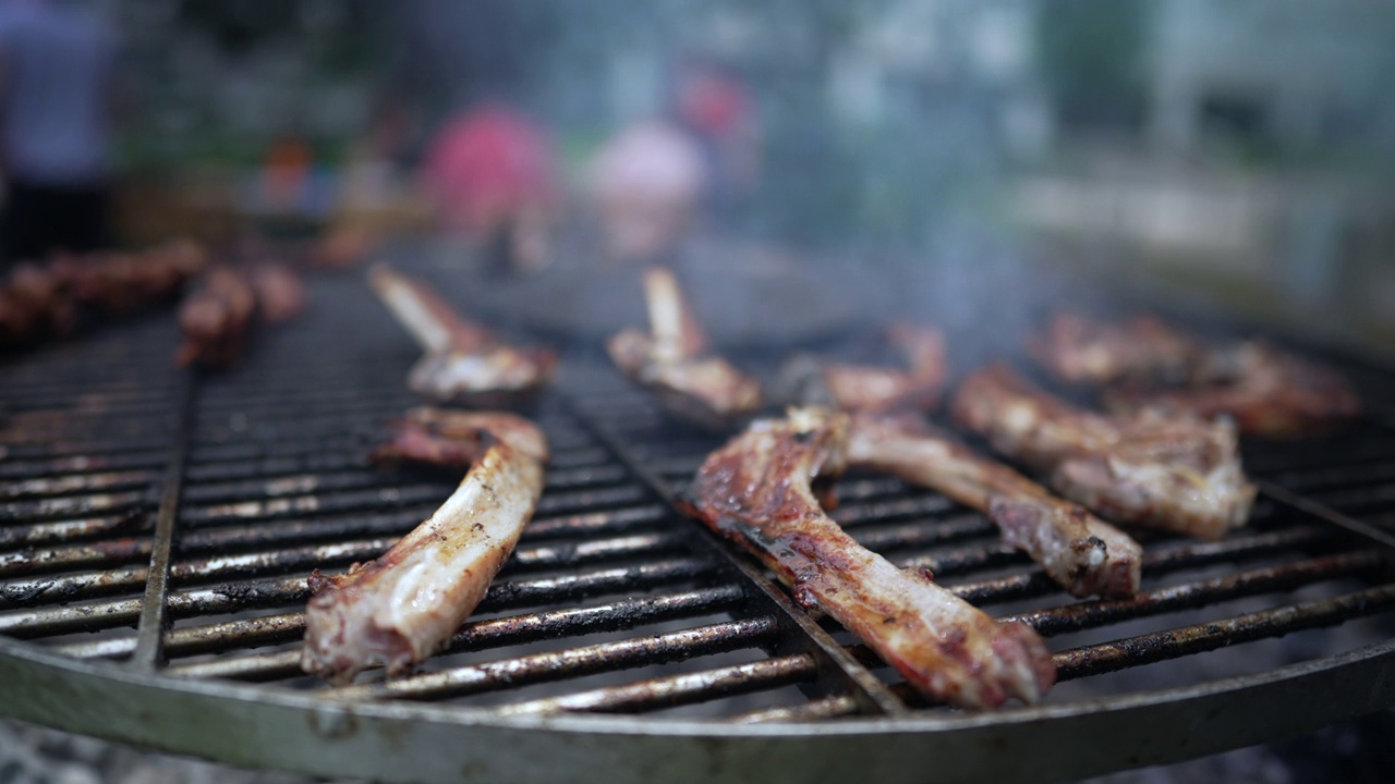 烤肉架上的肉慢镜头。近距离的烹饪食物排骨在户外烧烤架视频素材