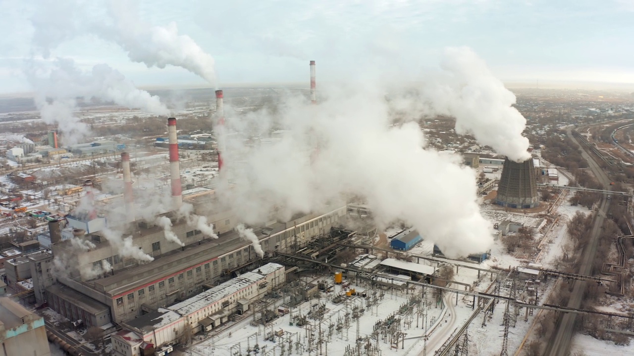 CHP的烟囱在烟雾缭绕的城市和白雪覆盖的平原的背景下冒着烟。b - roll视频素材