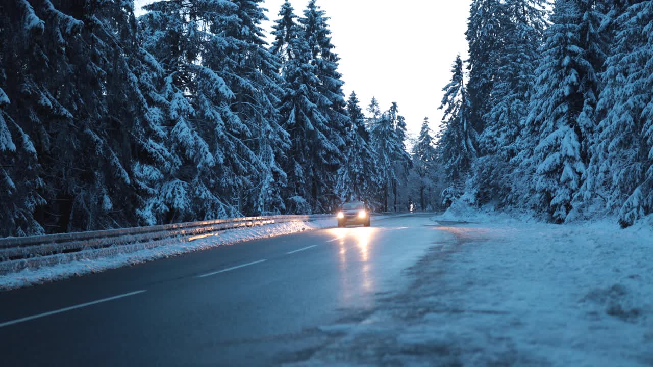 汽车行驶在寒冷的街道上，周围是蓝色的雪林视频下载