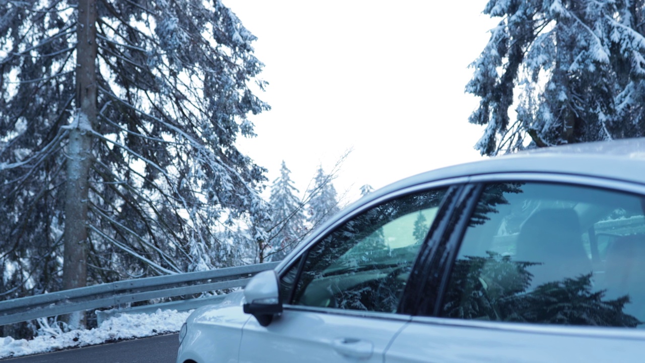 汽车行驶在白雪覆盖的冬日山路上，蓝色的冰色背景视频素材