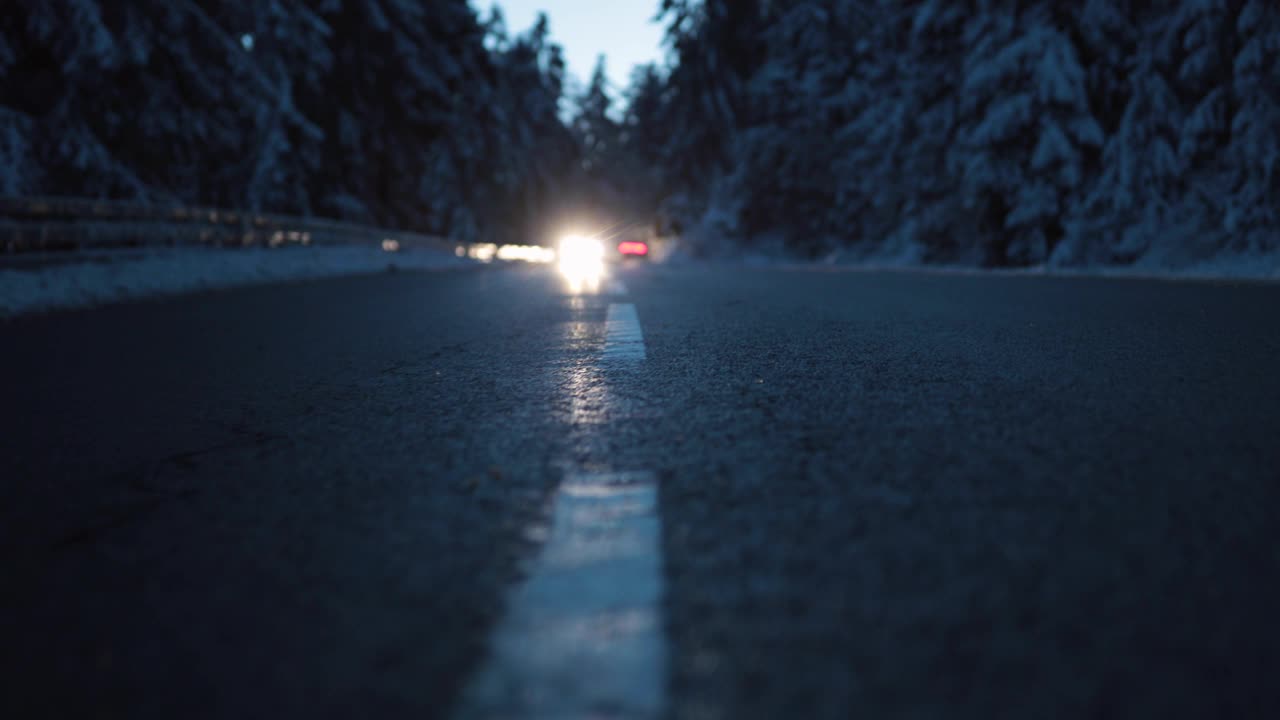 在白雪覆盖的森林里，汽车在远处可怕的冬天街道上行驶视频素材