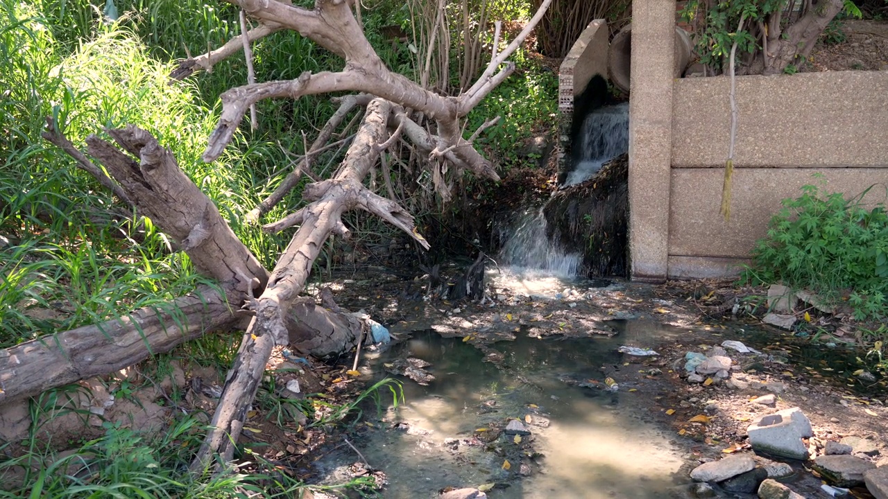 下水道的水和塑料垃圾在城市街道上流动。污染的概念，垃圾场，下水道，卫生设施，环境。视频素材