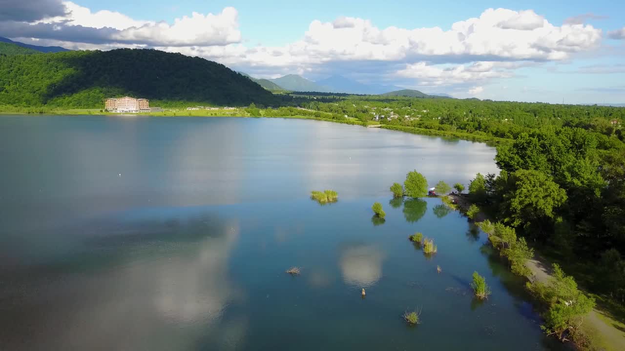 在春天的一个湖泊上，在阿塞拜疆的一个农村地区，绿色的树叶和树木周围的自然，蓝天白云的景观，在水中隐藏着美丽的天空视频素材