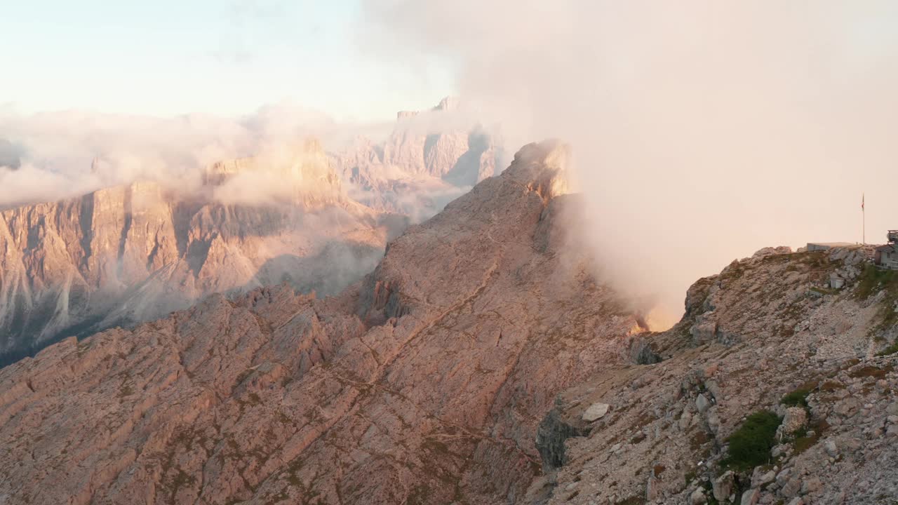 史诗无人机拍摄的山顶小屋在日落时被云层覆盖- Rifugio Nuvolau在五que Torri，白云石。视频素材