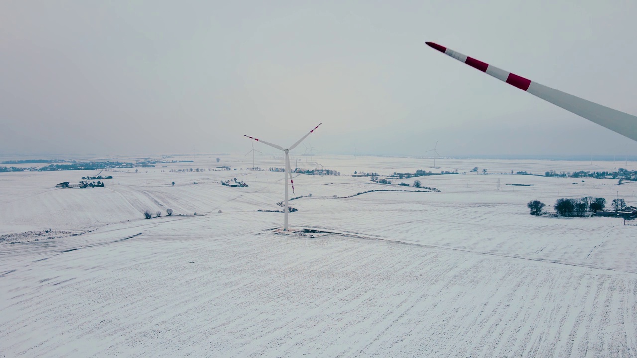 风车借助风力旋转，在寒冷的雪天冬天产生可再生能源视频素材