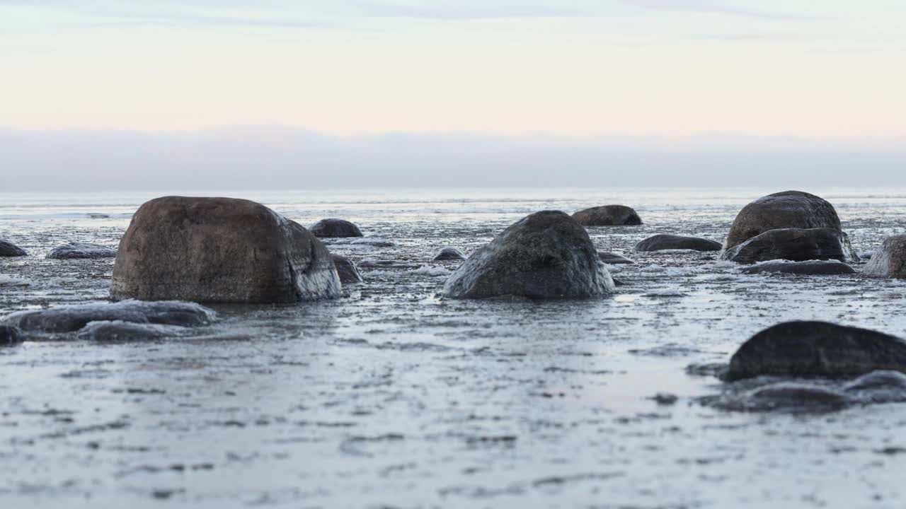 日落时分的波罗的海岸边，冰碎片特写。冬天的海景。气候变化视频素材