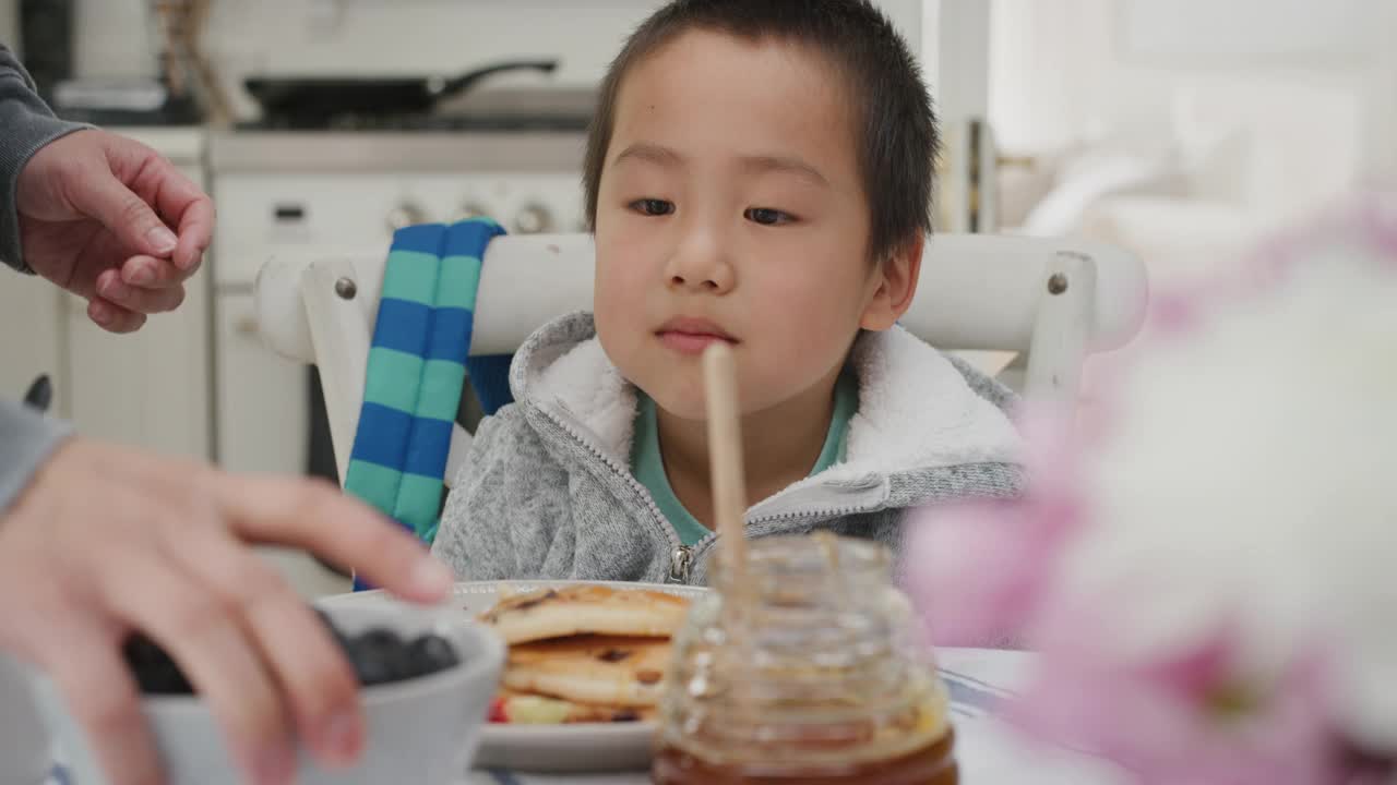 可爱的亚洲小男孩吃着新鲜的华夫饼当早餐，在家里的厨房里和家人一起享受美味的自制晚餐视频素材