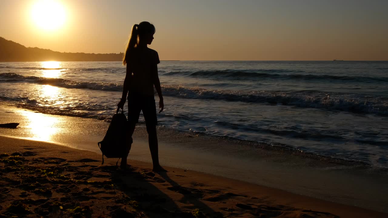 黄昏海湾上一个年轻旅行者的剪影。视频素材