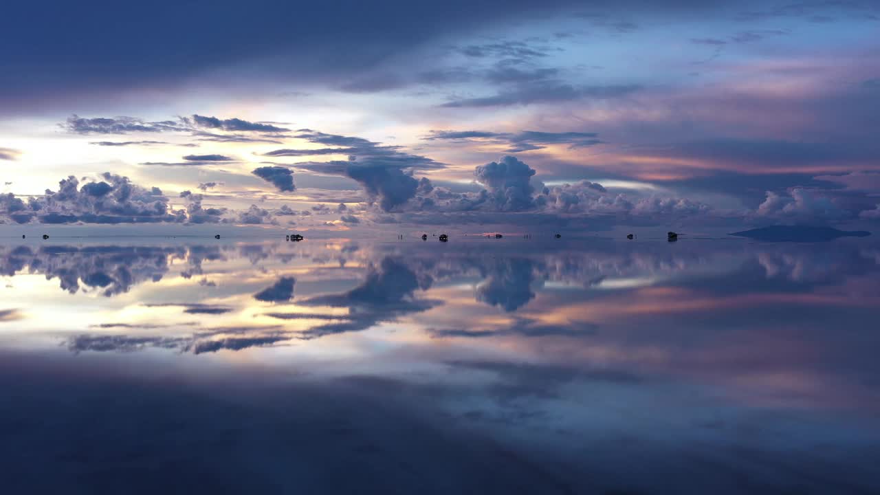 日落时分，多辆越野车散布在乌尤尼盐湖的地平线上。视频素材