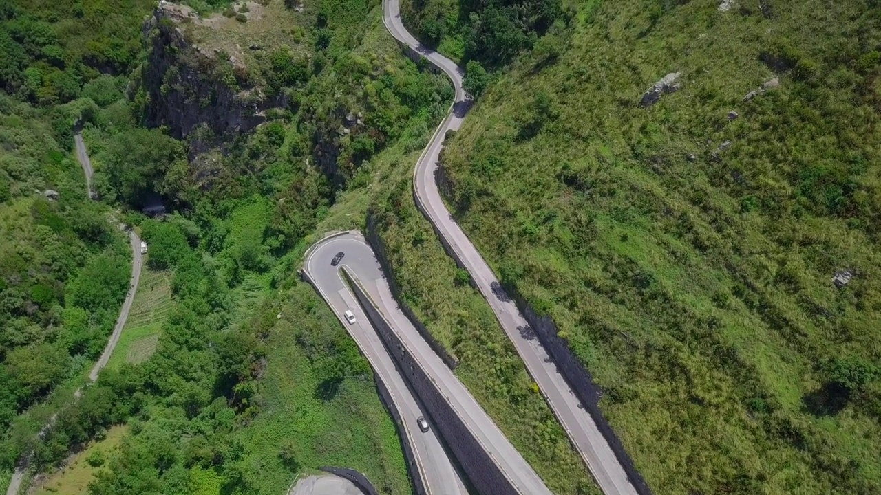 鸟瞰蜿蜒的蛇形道路，汽车行驶在弯弯曲曲的山路峡谷视频素材