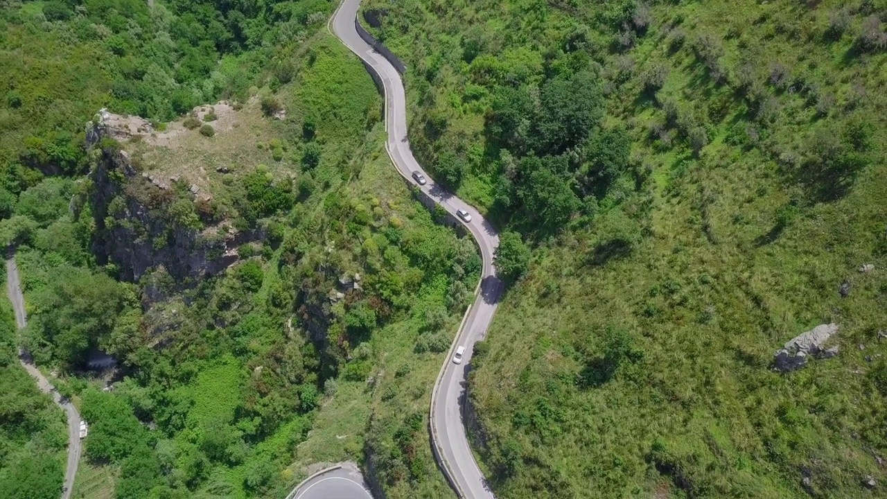 鸟瞰蜿蜒的蛇形道路，汽车行驶在弯弯曲曲的山路峡谷视频素材