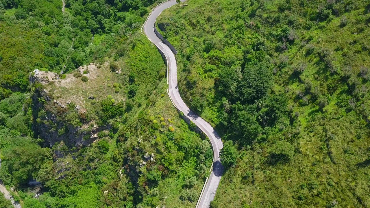 鸟瞰蜿蜒的蛇形道路，汽车行驶在弯弯曲曲的山路峡谷视频素材