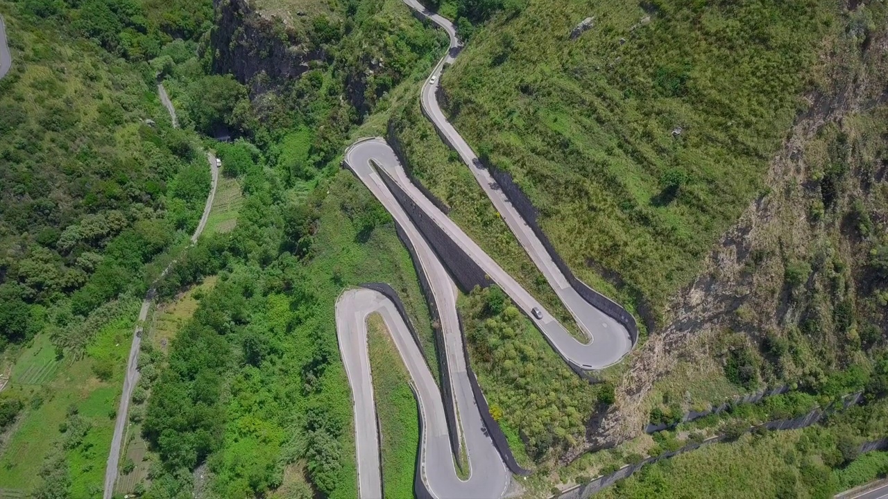 鸟瞰蜿蜒的蛇形道路，汽车行驶在弯弯曲曲的山路峡谷视频素材