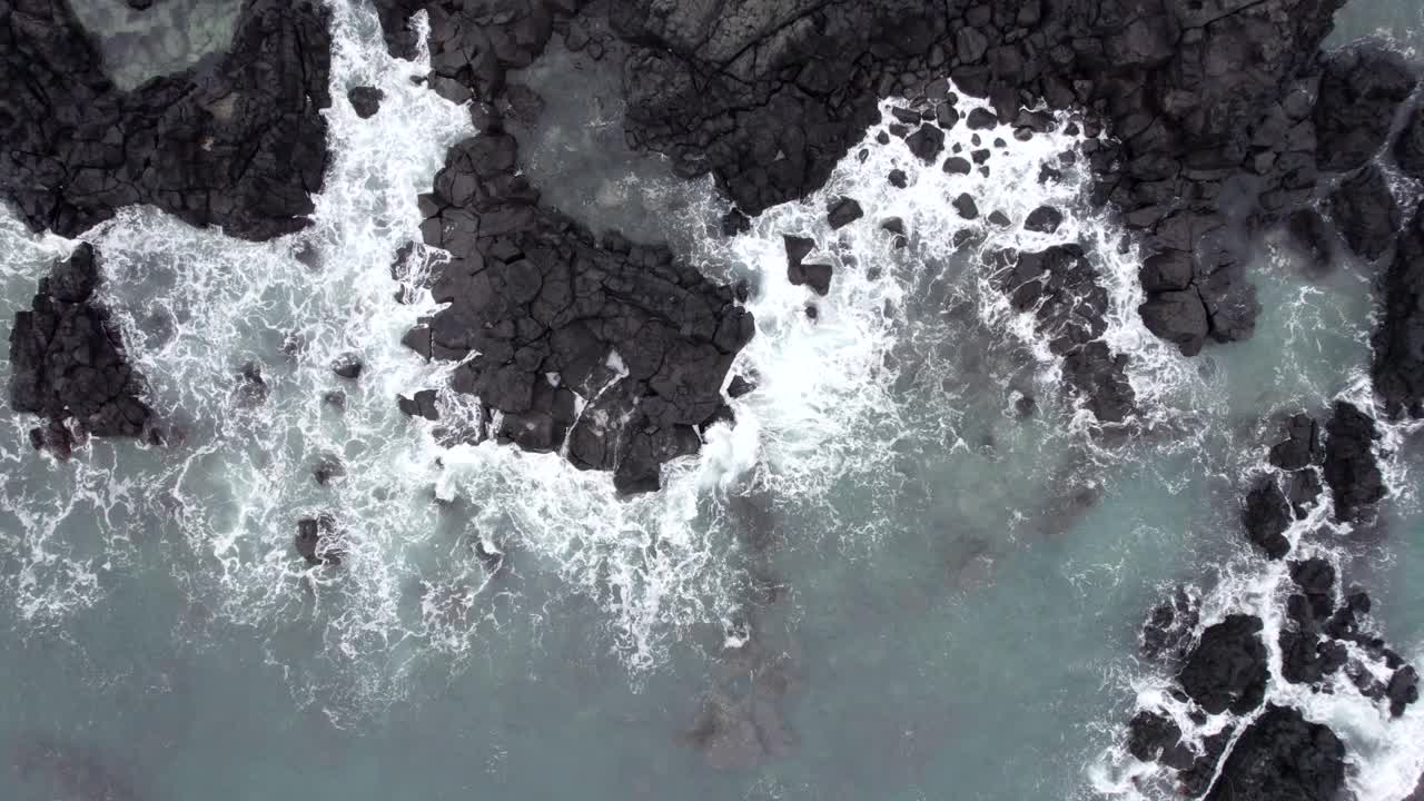 大海在黑色岩石上波浪起伏/济州岛，韩国视频素材