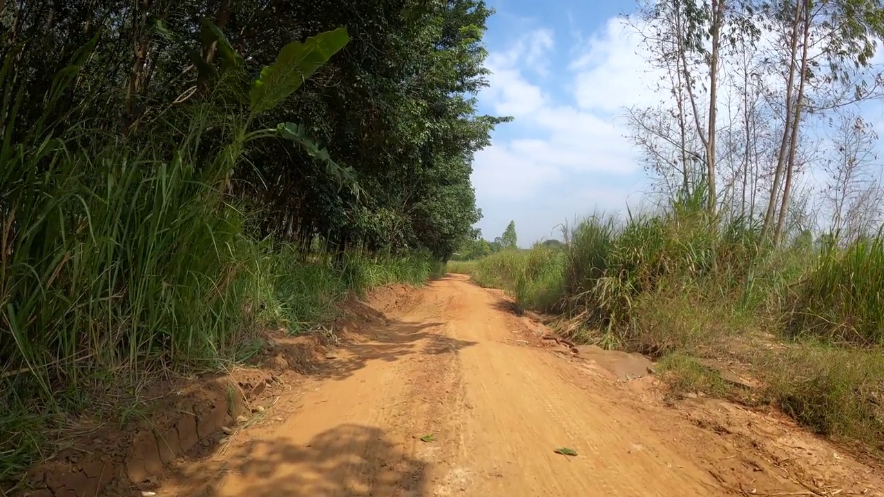 在土路上奔跑的观点。越野卡车的车轮在尘土飞扬、干湿泥泞的肮脏道路上行驶。在偏僻的地方旅行的观点视频素材