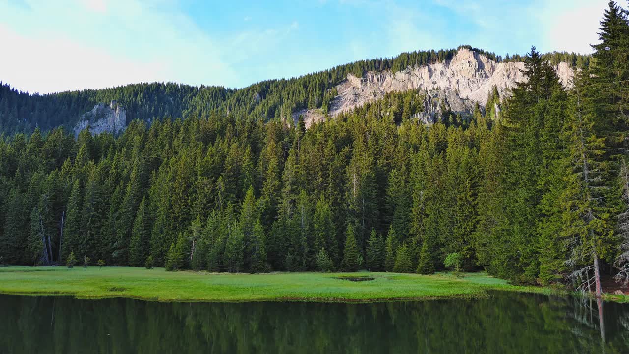 湖水反射着阳光，映衬着蓝天、山脉和村庄视频素材