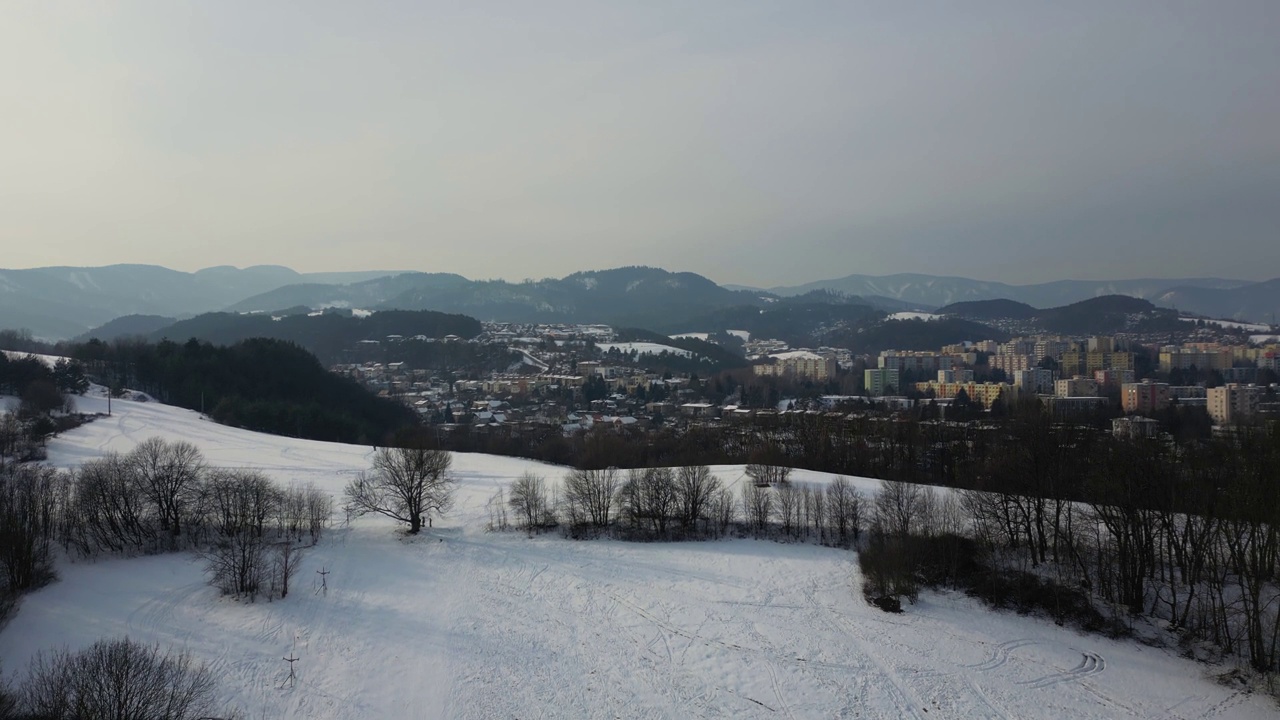 无人机从白雪覆盖的山上起飞，班斯卡比斯特里察的城市景观视频素材