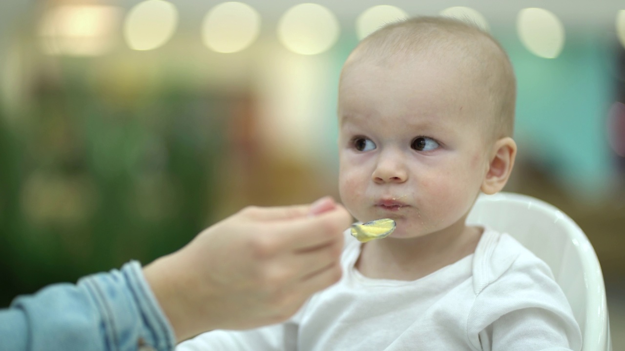 母亲给儿子喂婴儿食品。视频下载