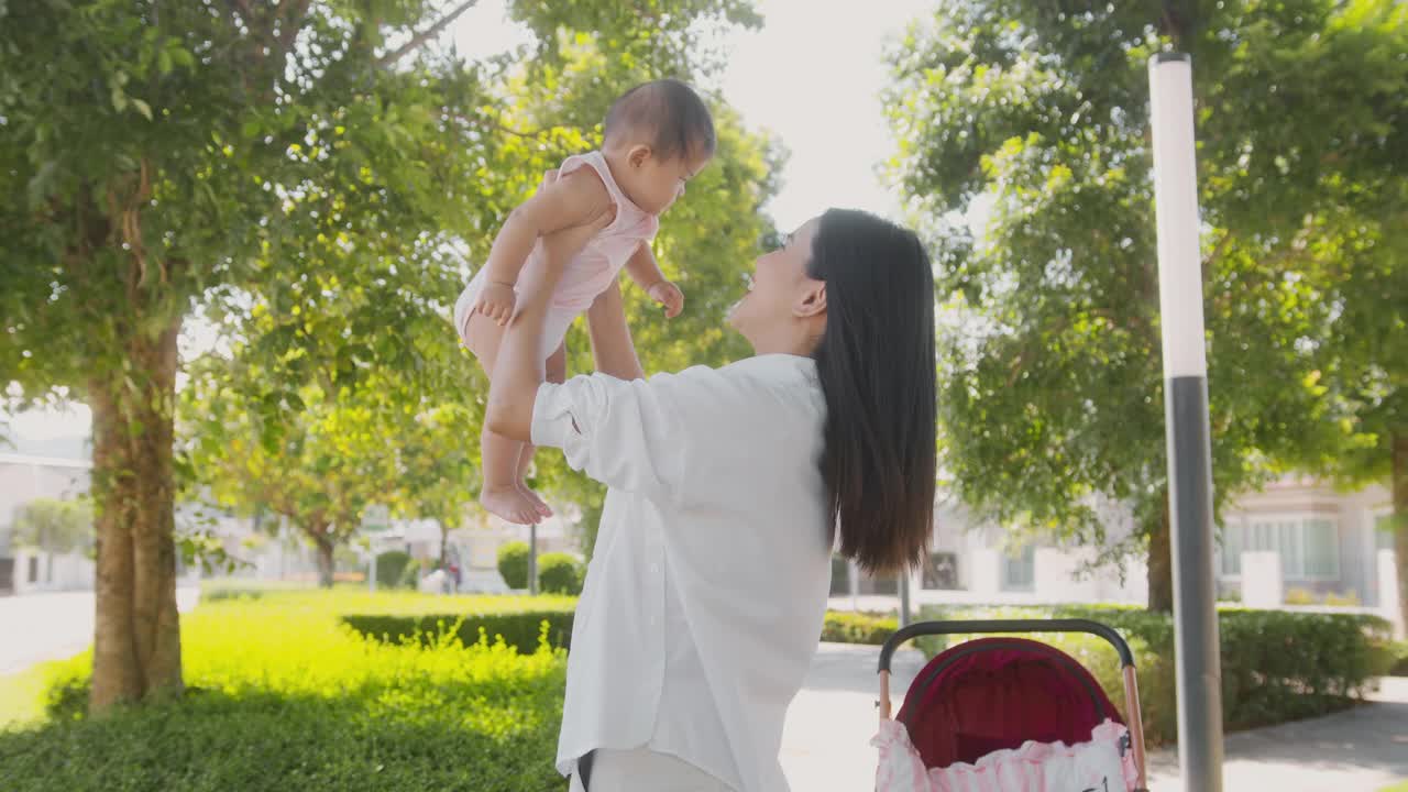 阳光明媚的户外，美丽的妈妈抱着一个女婴视频素材