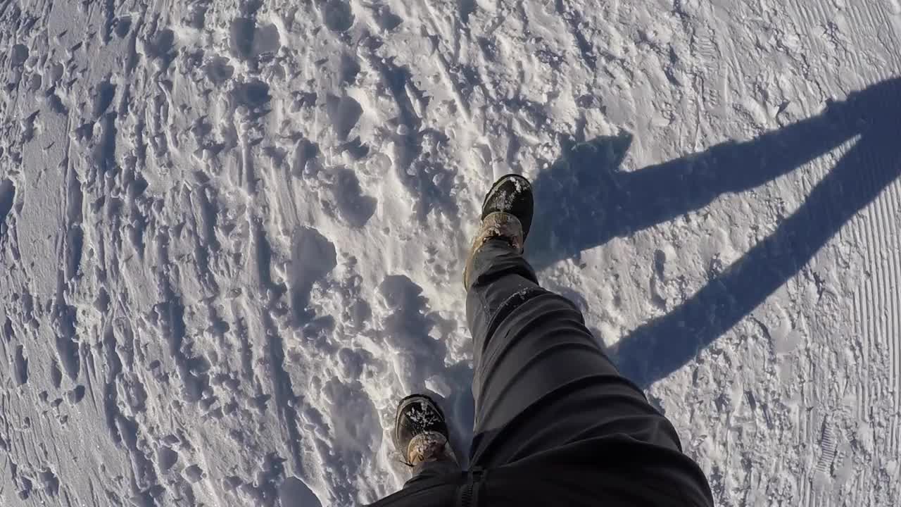 一个穿着灰色裤子的人在瑞士一条整洁的雪道上徒步旅行视频素材