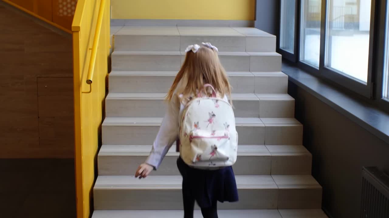 背着书包的女学生在学校的黄色楼梯上蹦蹦跳跳地跑着视频素材