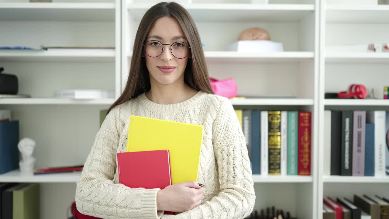 年轻美丽的西班牙女子站在图书馆大学拿着书视频素材