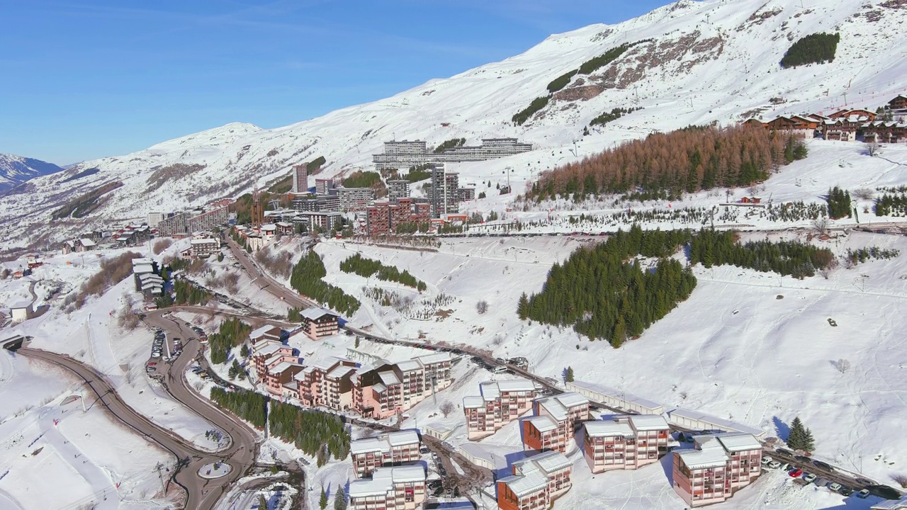 法国，Les Menuires:法国著名的阿尔卑斯山滑雪胜地(萨瓦阿尔卑斯山)冬季鸟瞰，阳光明媚，雪景丰富——从高处俯瞰欧洲全景视频素材