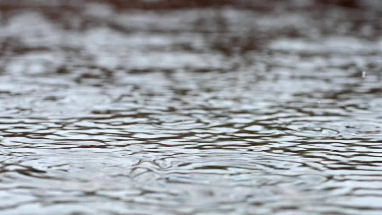 一滴细雨。水在慢动作中落入水坑。视频素材