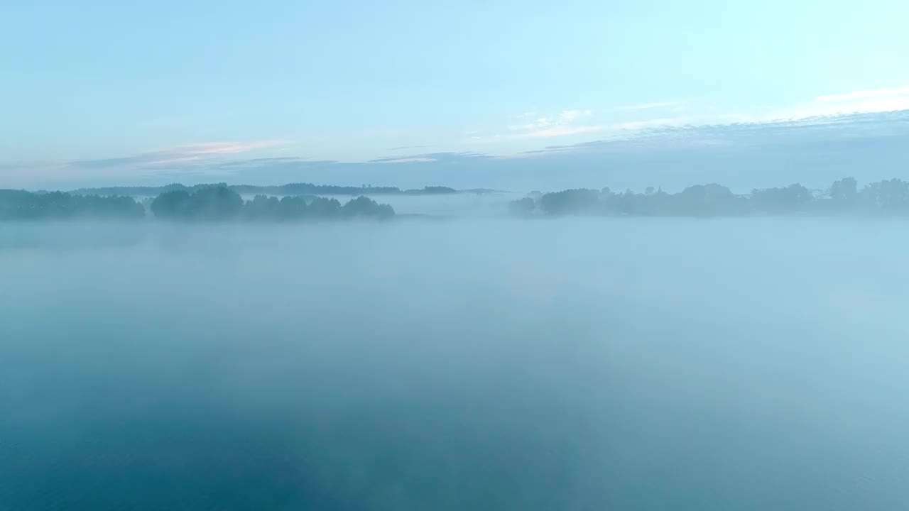 雾蒙蒙的早晨，在森林和田野环绕的美丽湖泊上。一个小村庄，坐落在雾和晨曦中湖附近。视频素材