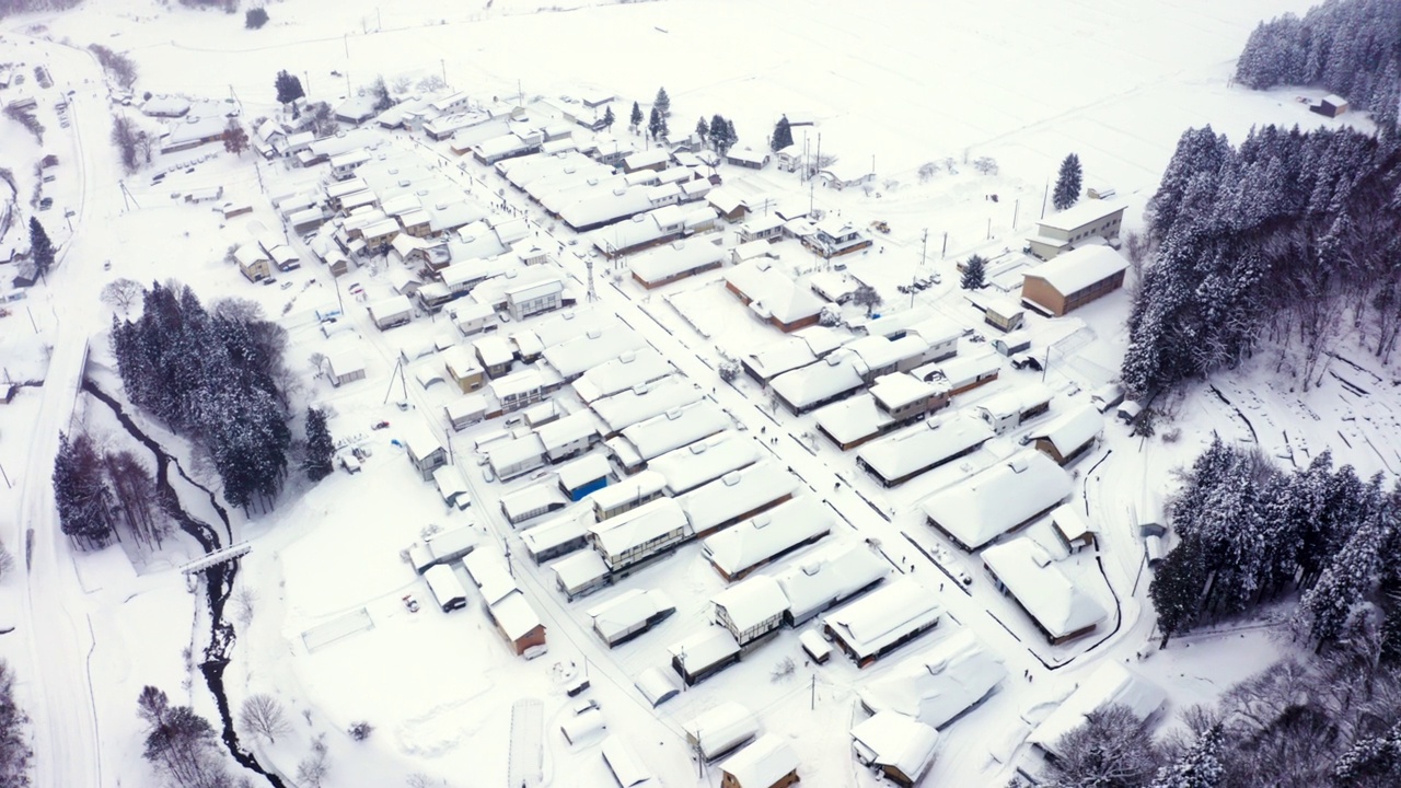 4K鸟瞰雪天山间的小村庄和河流。视频素材