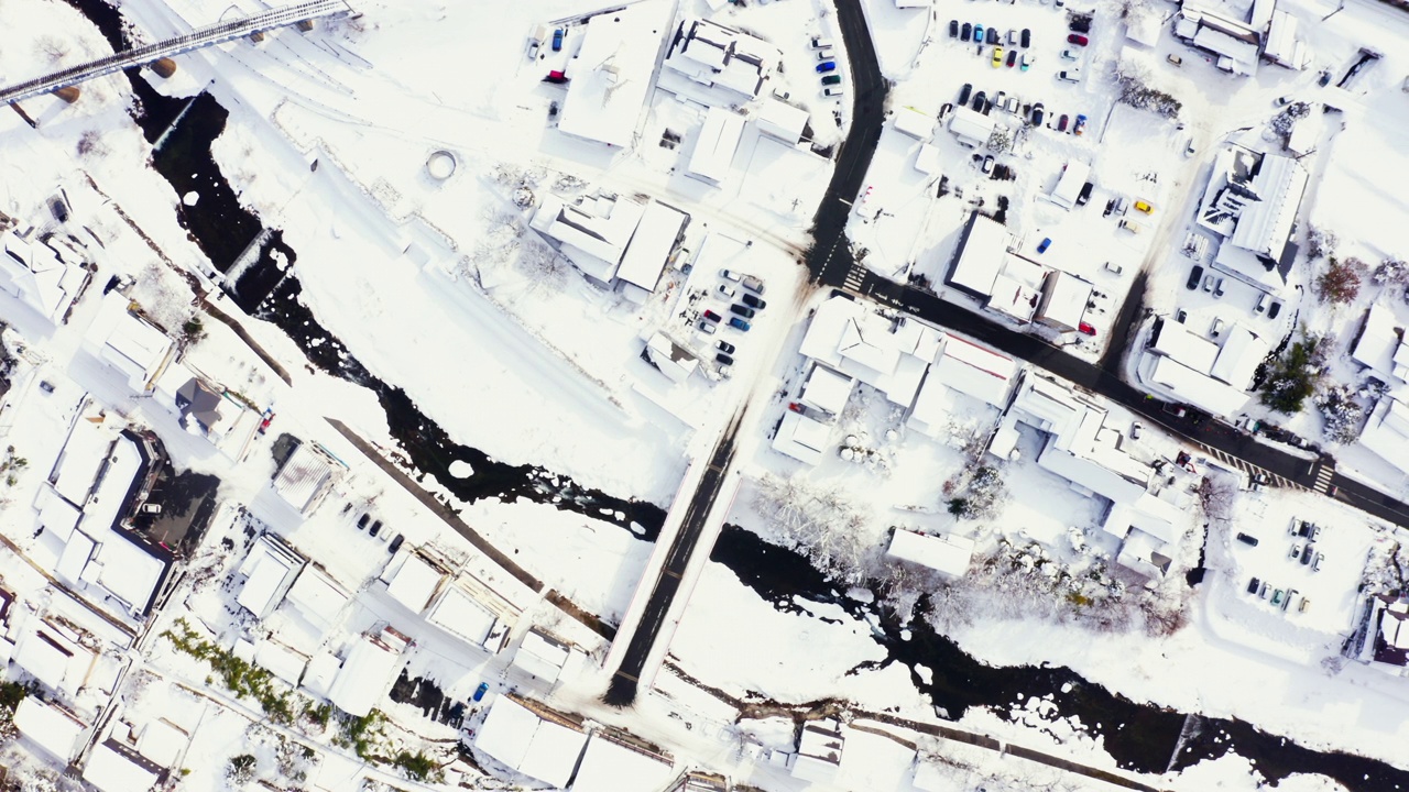 4K鸟瞰雪天山间的小村庄和河流。视频素材