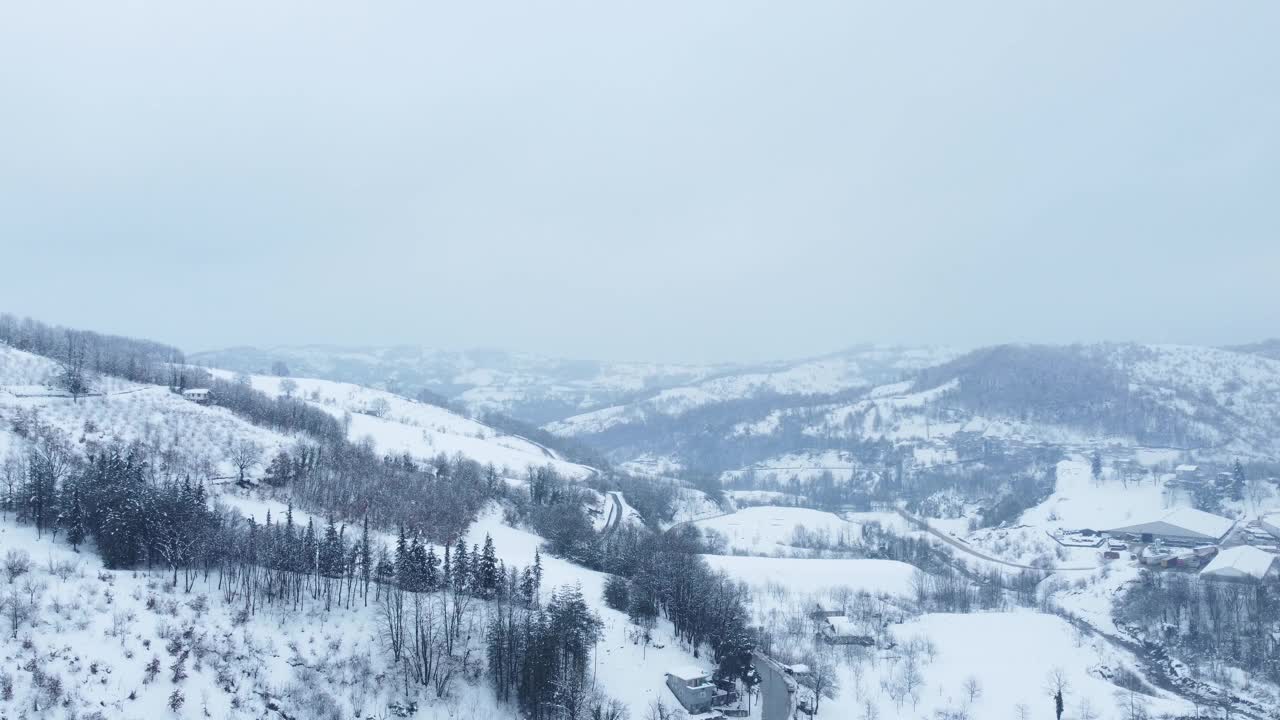 有树木和小径的雪地。山上的房子在冬天。鸟瞰图。视频素材