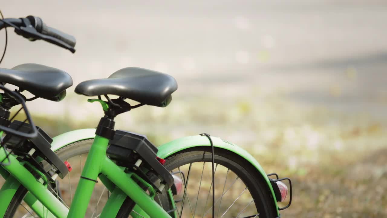 一名亚洲女性正在用手机解锁并乘坐公共自行车租赁服务。女游客租了一辆自行车在城市里旅游。视频下载