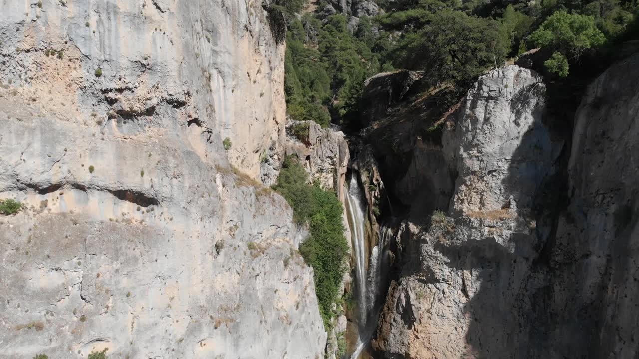 Salto de losórganos瀑布的倾斜镜头，清澈的水流穿过岩石，在悬崖底部形成一个池塘。视频素材