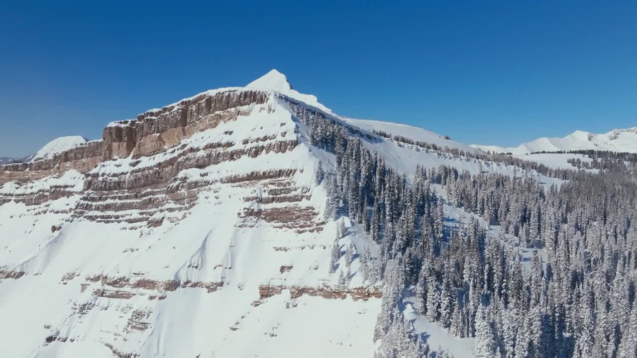 在晴朗的冬日，鸟瞰白雪覆盖的树木森林和美丽的山地景观视频素材