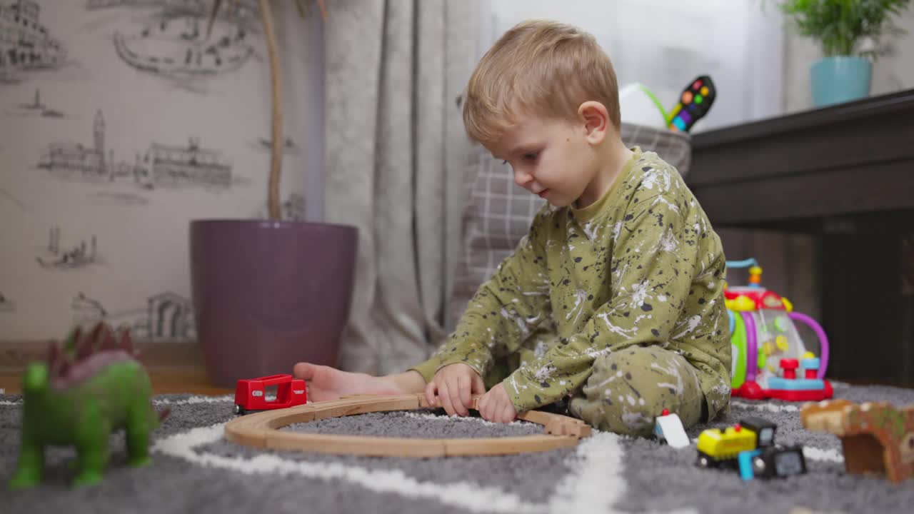 孩子在玩发育玩具。宝宝在地板上玩玩具火车、火车和汽车。在家或幼儿园的孩子视频素材