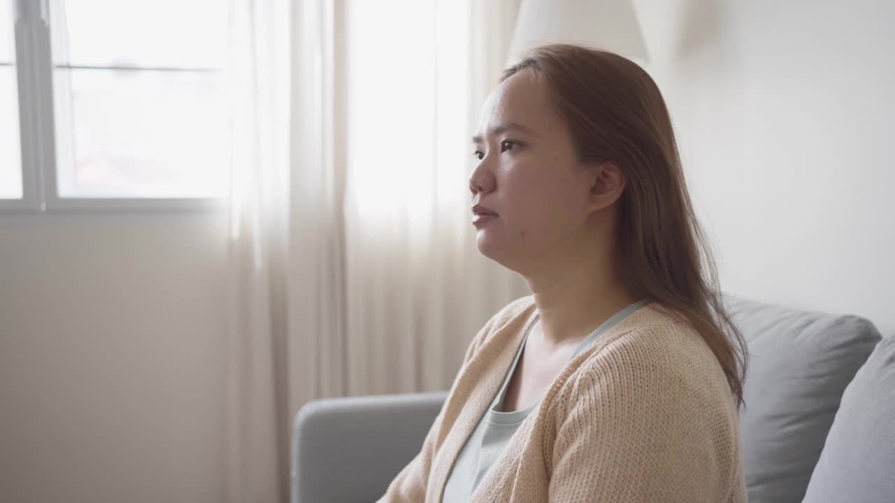 女人坐在沙发上，身体肩膀和背部疼痛，在客厅视频素材