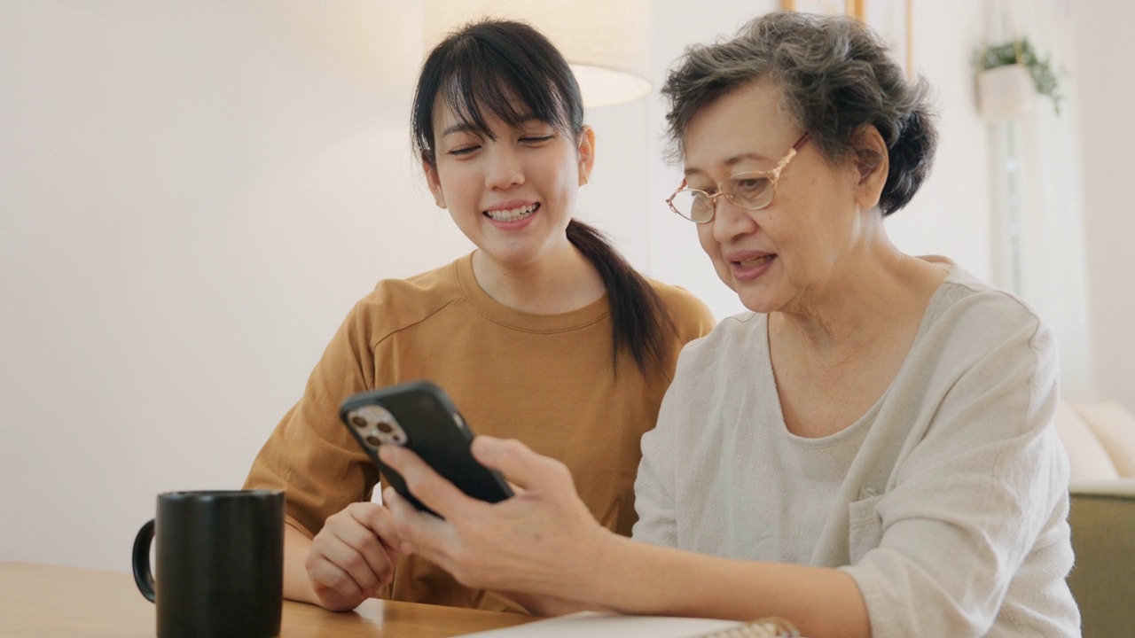 老年妇女向护工学习智能手机。视频素材