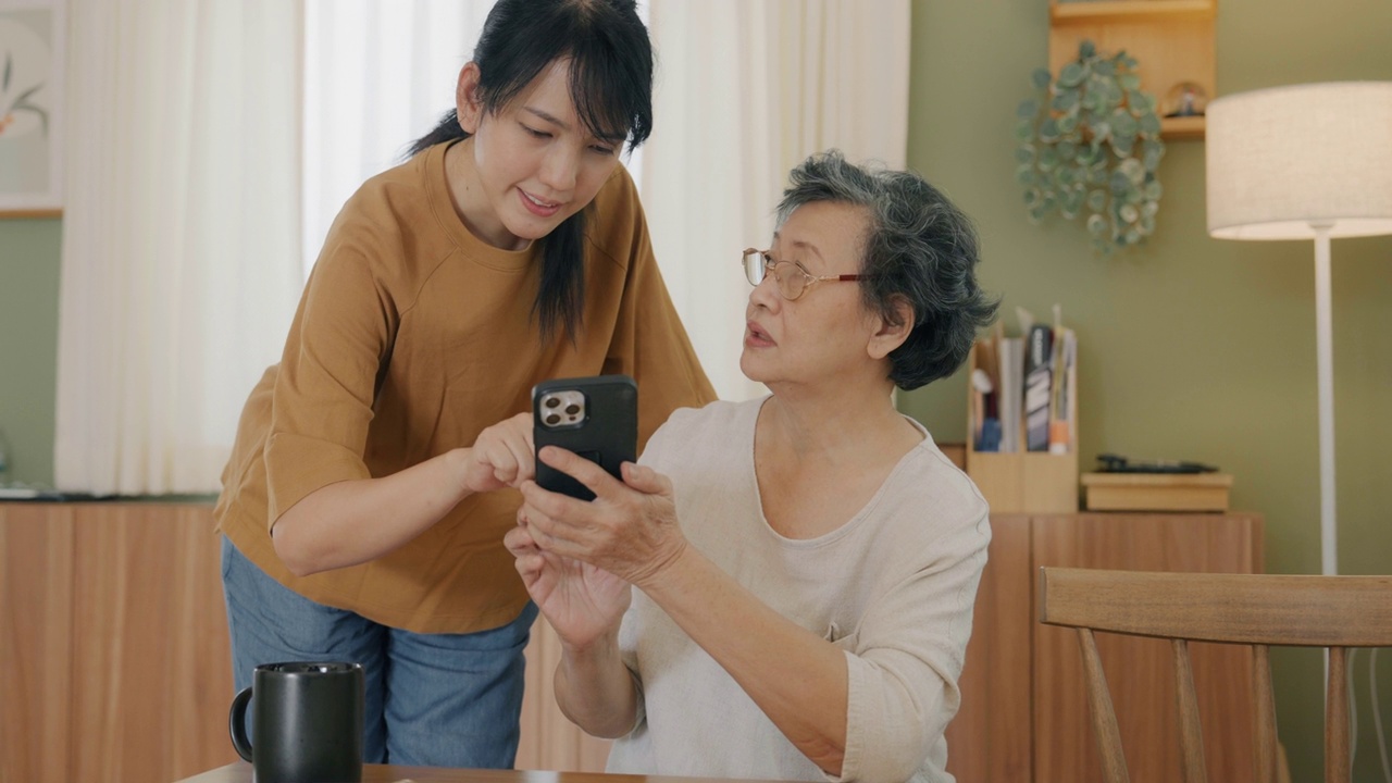 老年妇女向护工学习智能手机。视频素材