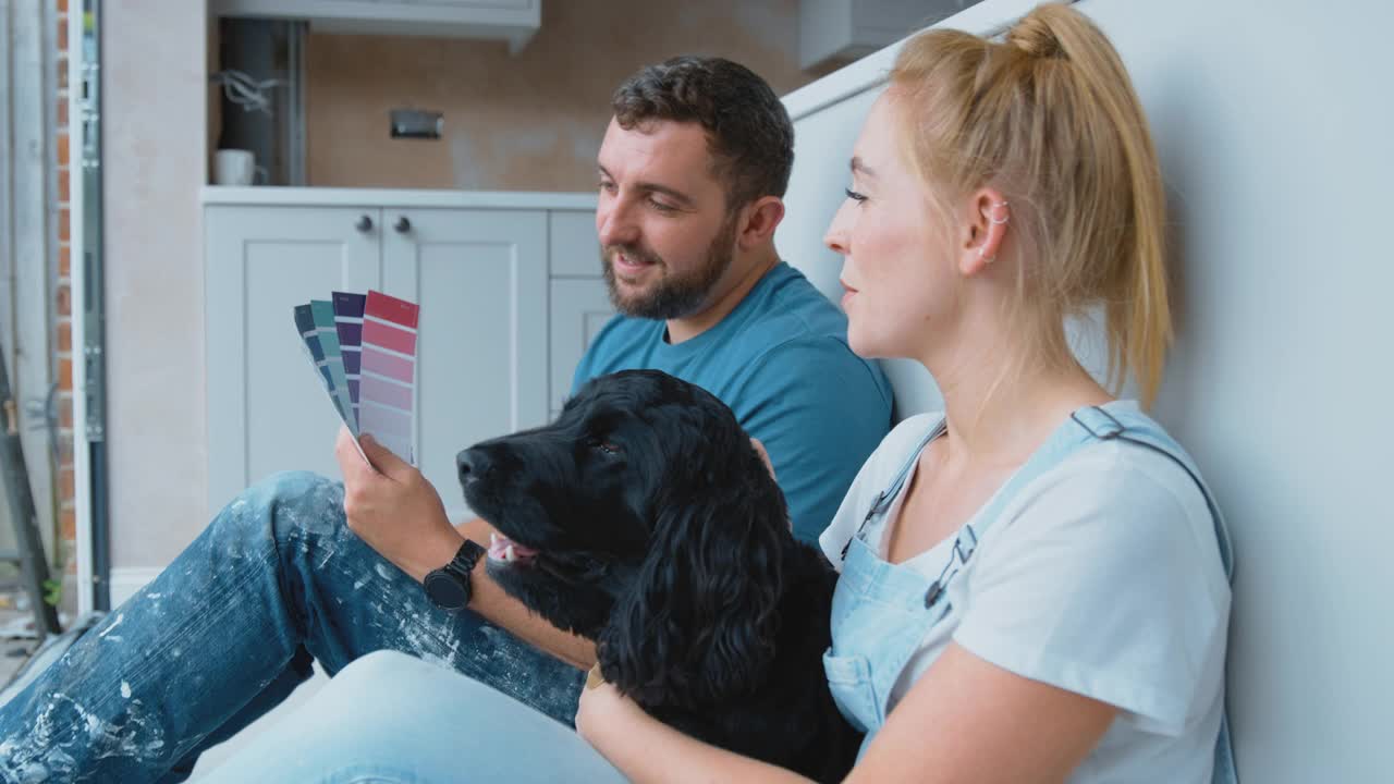 夫妇在咖啡休息时间从装修厨房在家里玩宠物西班牙犬看着油漆色板-拍摄在慢动作视频素材