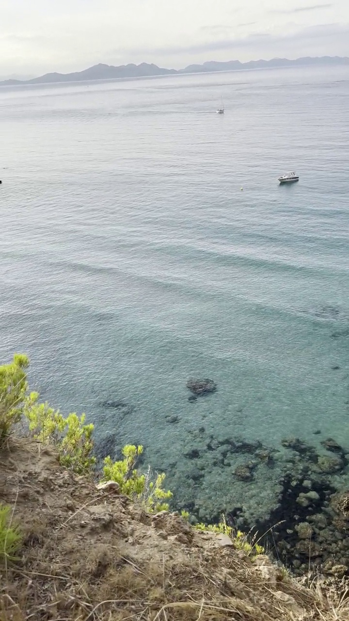 绿松石礁湖，岩石海滩和一些船。Cala Na Clara，马略卡岛，西班牙。视频下载