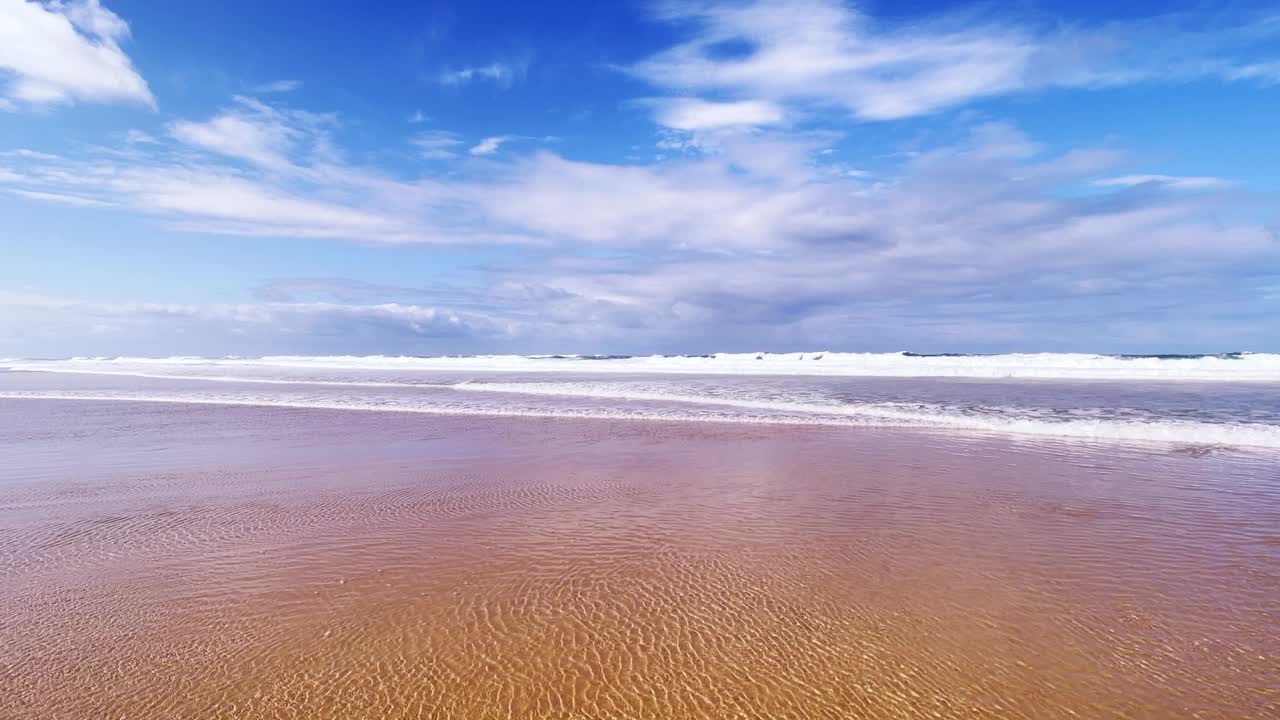 流动的水和破碎的海浪在海滩上一个阳光灿烂的日子与田园诗般的云视频素材